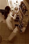 Femme debout au réfrigérateur, ayant poulet comme collation de minuit