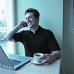 Homme assis à Table avec un ordinateur portable et le café, à l'aide de téléphone portable