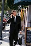 Mature Businessman Walking on Street Using Cell Phone