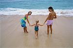 Grandmother, Mother and Daughter Holding Hands on Beach