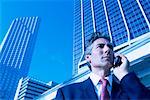 Mature Businessman Using Cell Phone by Office Towers