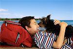 Boy Lying Outdoors with Dog Licking Face