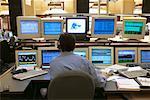 Back View of Man at Computers in Stock Market Trading Room