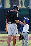 Back View of Boy in Baseball Uniform and Coach Outdoors