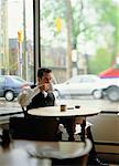 Waiter Sitting at Table in Cafe Drinking from Mug