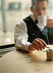 Waiter Sitting at Table in Cafe Smoking Cigarette and Drinking From Mug