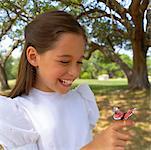 Fille portant robe avec jouet papillon sur le doigt à l'extérieur