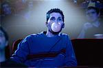 Young Man Watching Movie in Theatre, Blowing Bubble