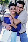 Portrait of Couple Embracing and Holding Shopping Bags Outdoors