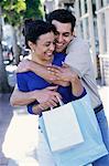 Couple Embracing and Holding Shopping Bags Outdoors