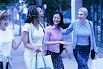 Four Women Walking Outdoors Carrying Shopping Bags