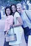 Portrait de trois femmes avec sacs à provisions en plein air