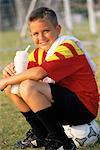 Garçon assis sur le ballon de Soccer