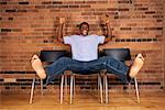 Man Sitting on Chair With Arms and Legs in Air