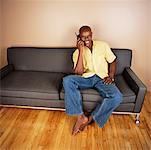Homme assis sur un canapé parlait au téléphone cellulaire