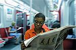 Woman Reading Newspaper on Subway Train