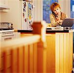 Femme utilisant un ordinateur portable dans la cuisine