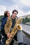 Young Woman listening to Young Man playing Saxophone
