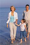 Grands-parents marche avec petite fille sur la plage