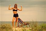 Woman Standing on Beach Flexing Muscles