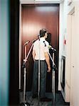 Businessman Standing in Front of Microphones, Facing Door