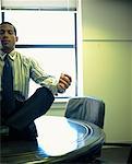 Man Meditating on Boardroom Table