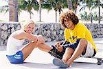 Young Man and Young Woman with In-Line Skates and Skateboard