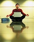 Man Meditating on Boardroom Table With Laptop