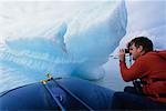 Man Taking Photograph of Iceberg