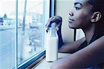 Frau Looking aus Fenster mit Flasche von Milch auf Fensterbrett