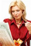 Woman Eating Breakfast and Reading Newspaper