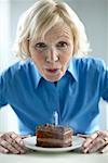Woman Blowing Candle on Piece of Cake