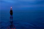 Woman Standing in Water at Night, Holding Light