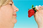 Large woman looking at strawberry