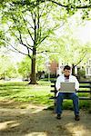 Teenager Using Laptop on Park Bench