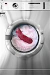 Rote Socke mit weißen Kleidung In der Waschmaschine