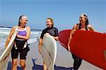 Trois femmes portant des planches de surf