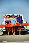 Three Woman Holding a Surfboard