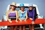 Three Woman Holding a Surfboard