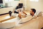 Man Sitting on Couch, Reading Newspaper