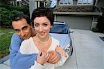 Couple Standing in Front of New Car and House