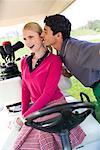 Man Leaning in to Kiss Woman in Golf Cart