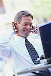 Businessman Using Laptop Computer, Talking on Cellular Phone