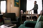 Man Standing in Room, Laptop Computer in Foreground