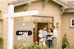 Gruß Familie zu Hause mit verkauften Schild Grundstücksmakler