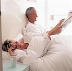 Couple Reading Newspaper in Bed
