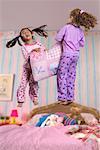 Zwei Mädchen bei einem Sleepover, springen auf dem Bett