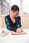 Woman Writing and Using Cellular Telephone