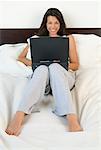 Femme utilisant un ordinateur portable dans le lit
