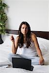 Femme assise sur le lit avec ordinateur portable